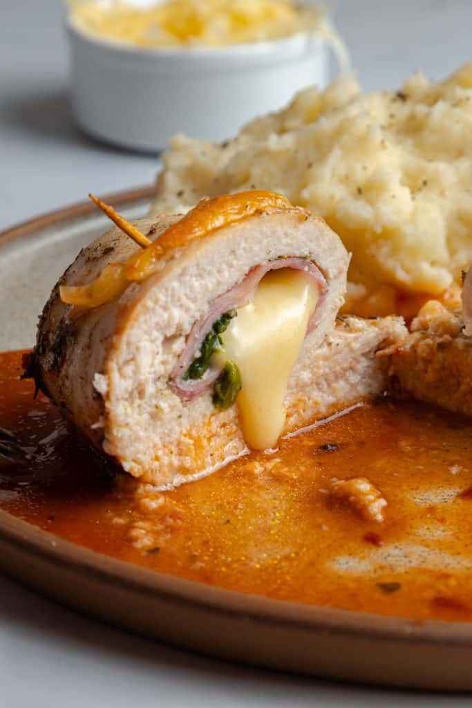 Chicken roll ups sliced to show ham, mozzarella, and spinach inside