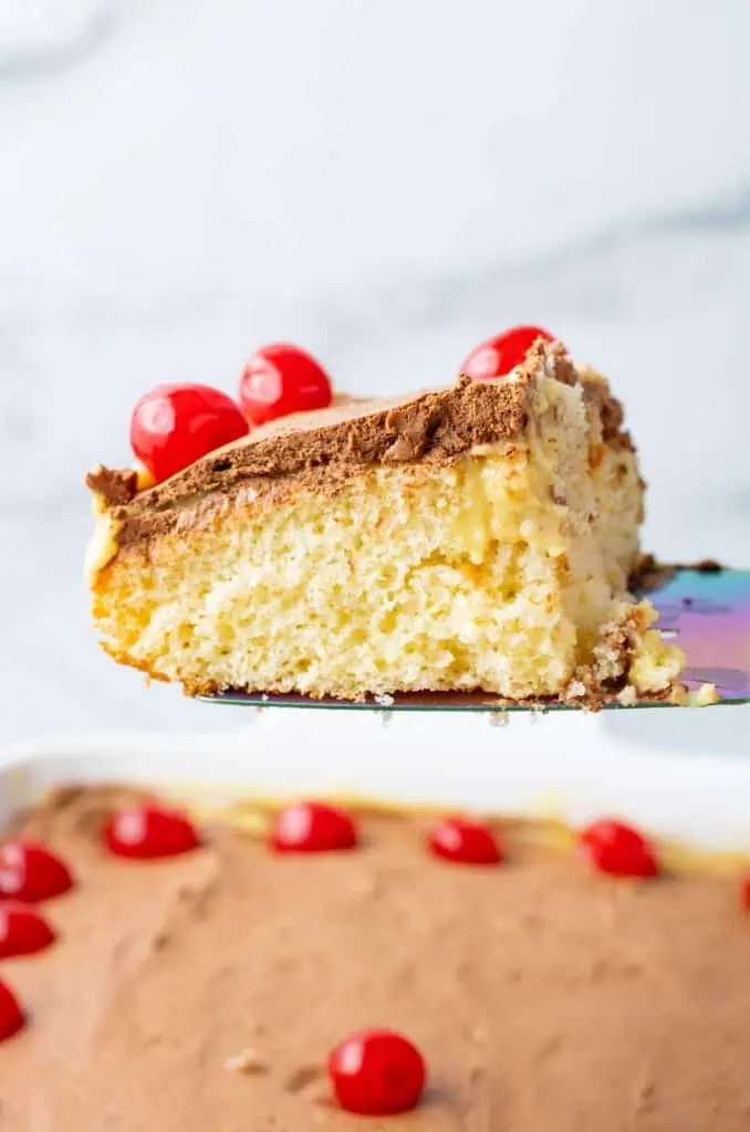 Close-up slice showing yellow cake, pudding pockets, and whipped ganache