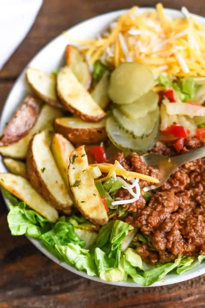 Close-up of saucy sloppy joe meat over roasted wedges and lettuce