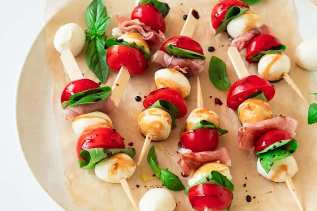 Easy Italian Caprese appetizer skewers arranged on a white serving platter with parchment paper