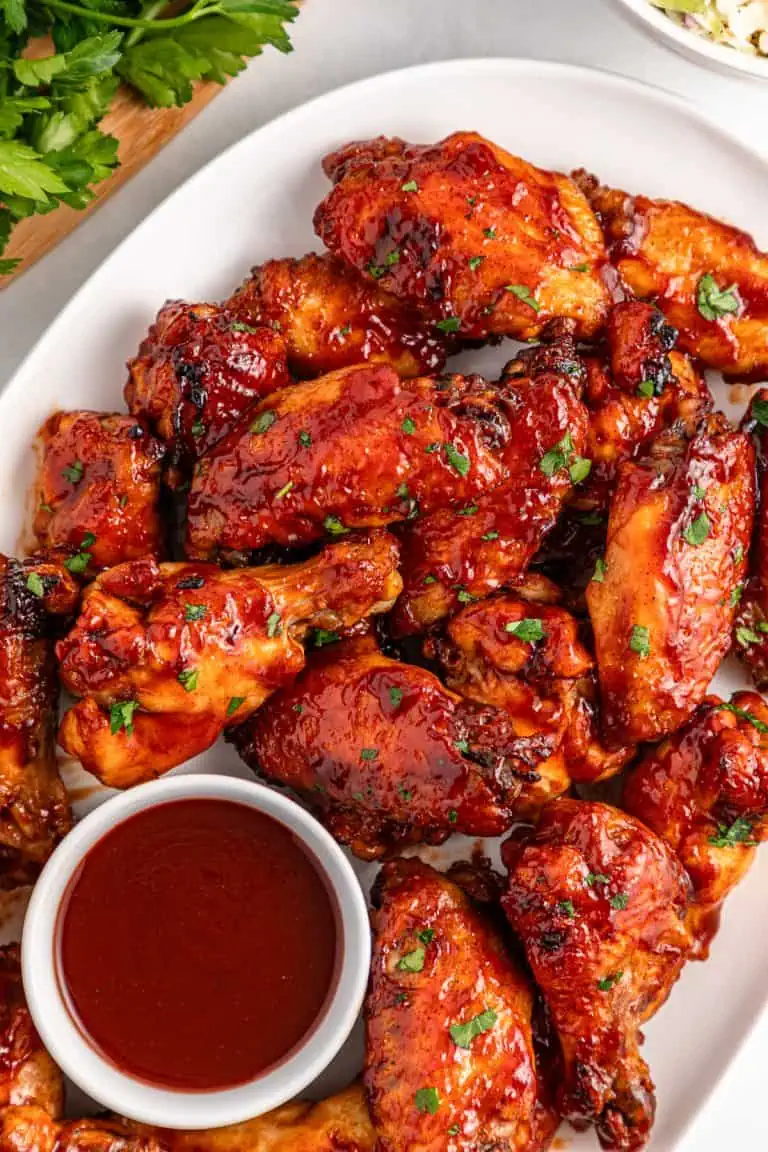 Slow cooker BBQ chicken wings served at a game day table with ranch dressing, celery, and party appetizers.