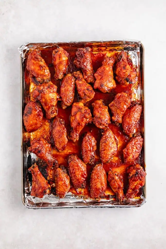 BBQ sauce glazed chicken wings made in a slow cooker and broiled in the oven on a metal cooking tray.