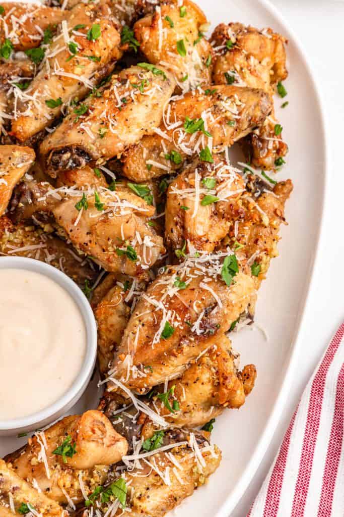 Chicken wings, grated parmesan, minced garlic, parsley, and seasonings arranged overhead with a a red and white striped napkin