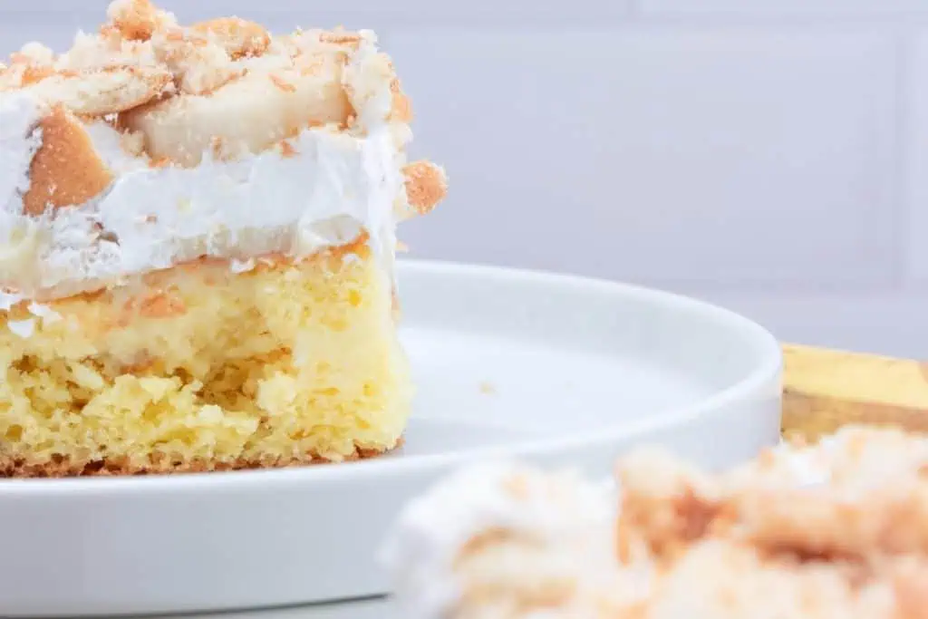 Close up view of a slice of banana pudding poke cake on a white plate
