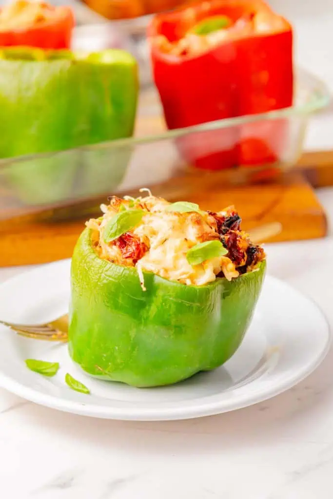 Single stuffed pepper on a white plate, fork resting alongside, natural light from a kitchen window highlighting the golden Parmesan topping