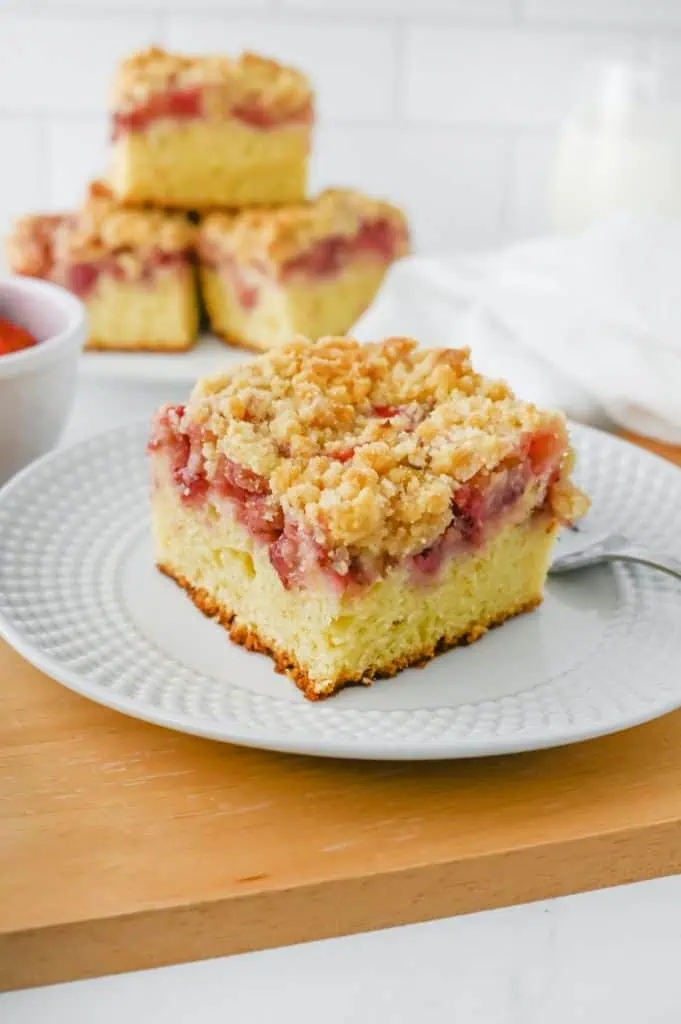 Close-up of a slice of strawberry crumb cake showing the soft vanilla cake base, ruby-red strawberry layer, and thick crumble topping