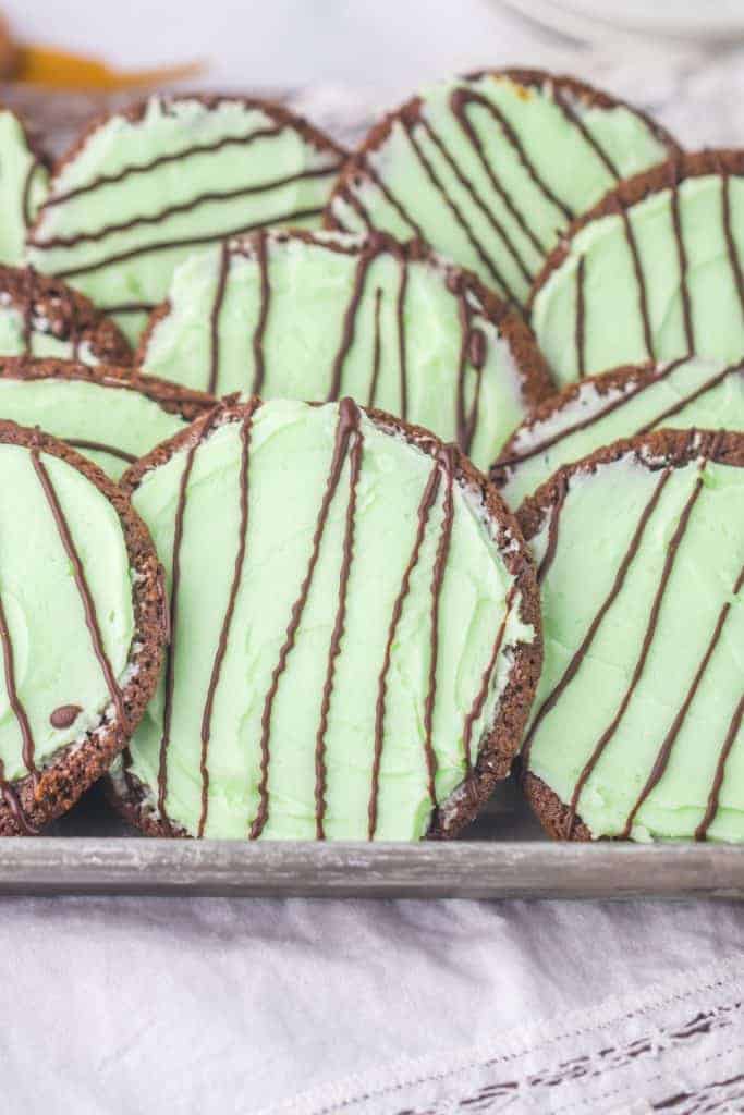 Close-up of a soft thin mint chocolate cookies showing creamy mint green frosting under thin ribbons of hardened chocolate drizzle