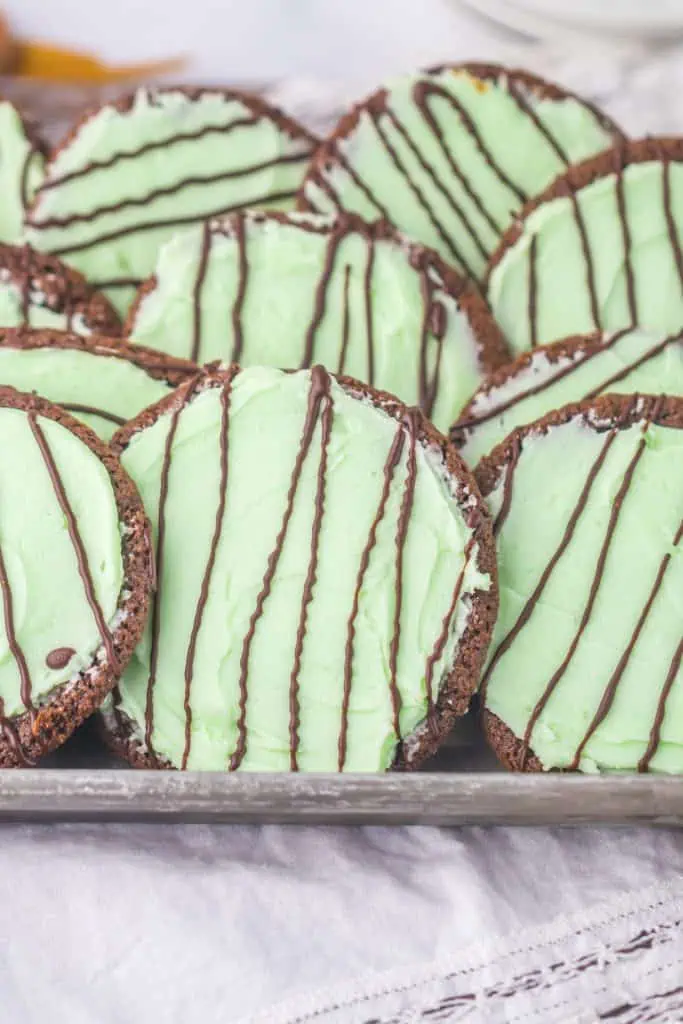 Close-up of a soft thin mint chocolate cookies showing creamy mint green frosting under thin ribbons of hardened chocolate drizzle