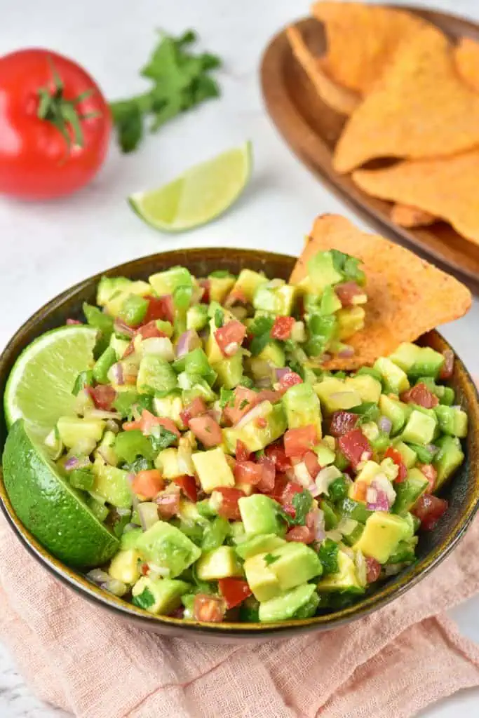 Close-up of chunky avocado salsa showing diced avocado cubes coated in olive oil and smoky paprika with flecks of red onion and cilantro