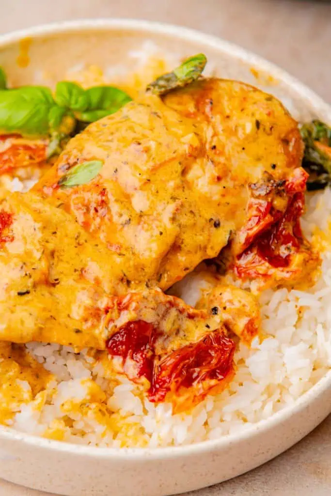 overhead photo of Marry me chicken served in a wide shallow bowl served over white rice and fresh basil to garnish