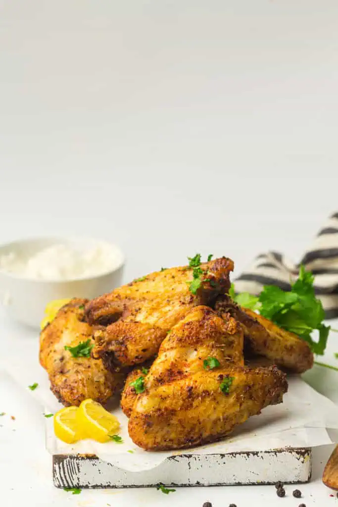 Close-up of crispy air fryer chicken wing skin with blistered golden-brown edges, cracked pepper, and chopped parsley