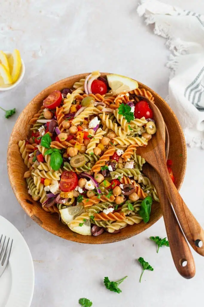 Close-up of Mediterranean pasta salad showing glossy dressed rotini, creamy feta chunks, briny kalamata olives, and fresh parsley
