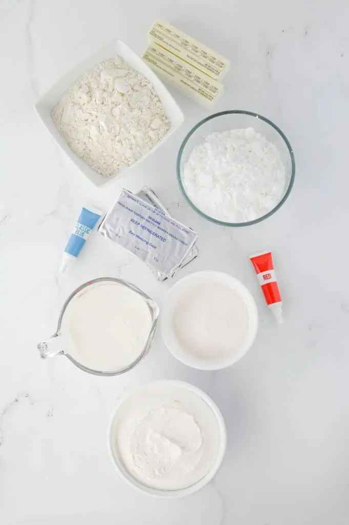 Red white and blue lush ingredients arranged overhead with flour, butter, cream cheese, cheesecake pudding mixes, milk, Cool Whip, and gel food coloring