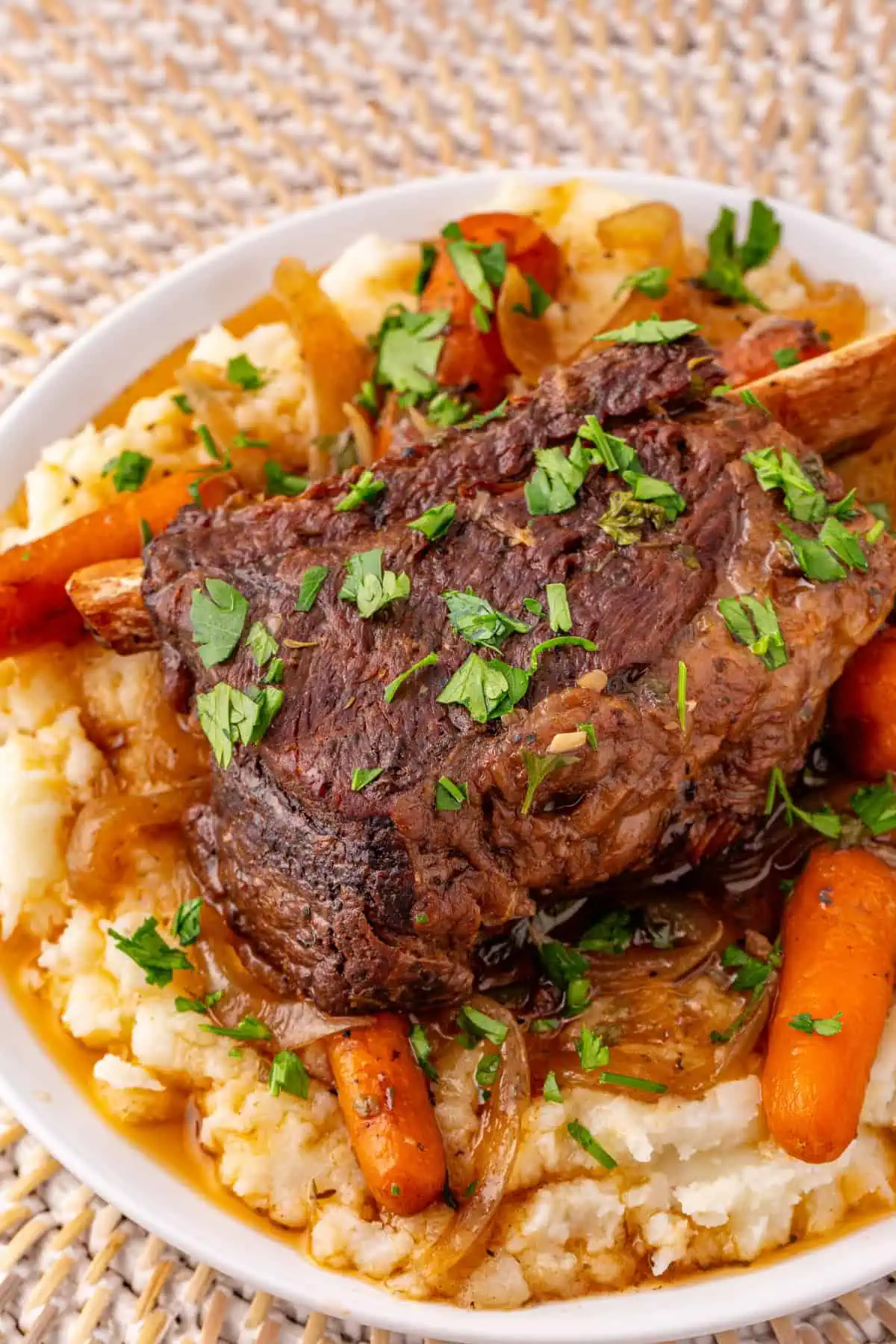 Crockpot beef short ribs over creamy mashed potatoes with red wine gravy and fresh parsley