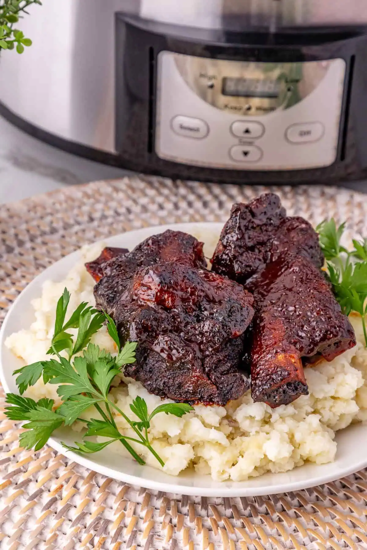 Crockpot BBQ beef ribs plated with creamy mashed potatoes and fresh parsley