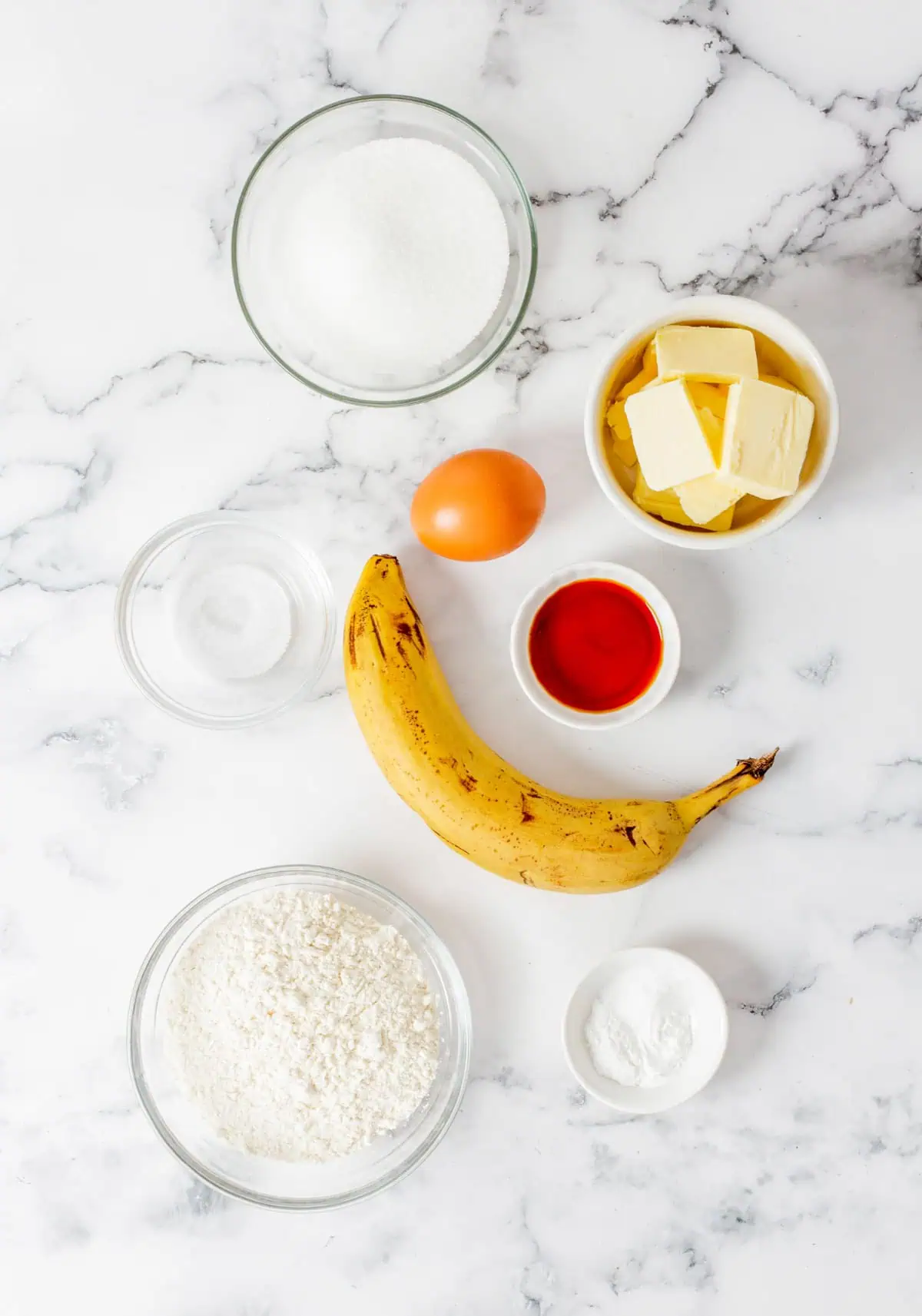 Ripe spotted bananas, flour, eggs, butter, and sugar laid out for moist banana bread