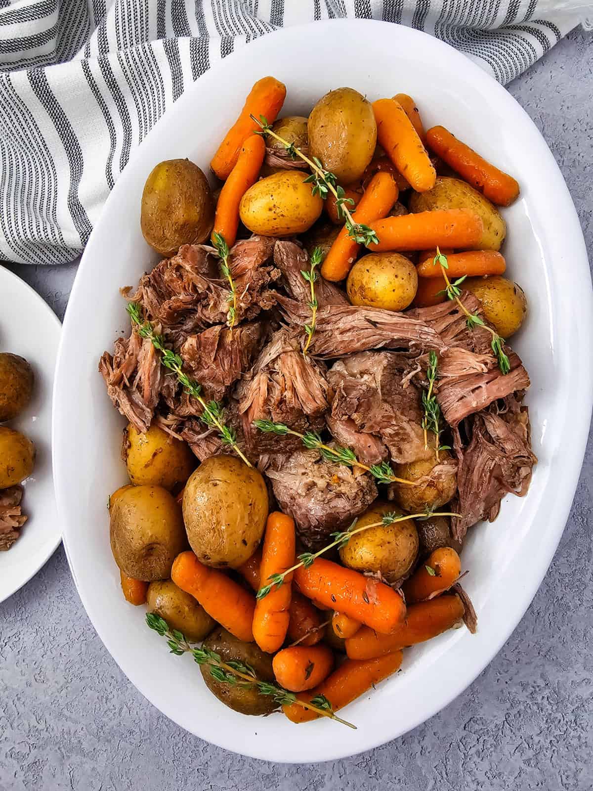 Fall-apart slow cooker chuck roast on a platter surrounded by tender potatoes and carrots