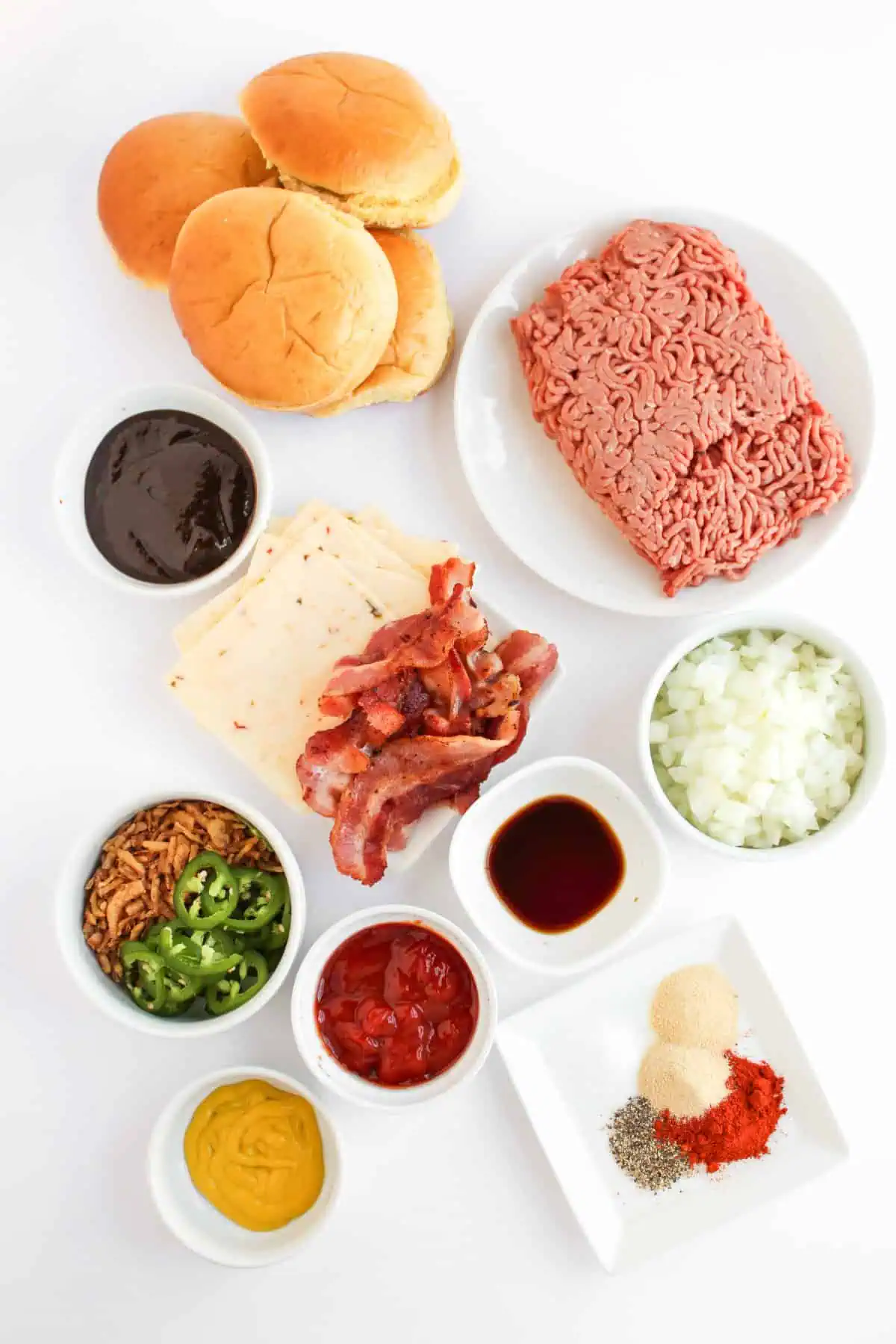 Ground beef, BBQ sauce, bacon, pepper jack, diced onions, jalapeno, and crispy onions laid out for BBQ cowboy sloppy joes