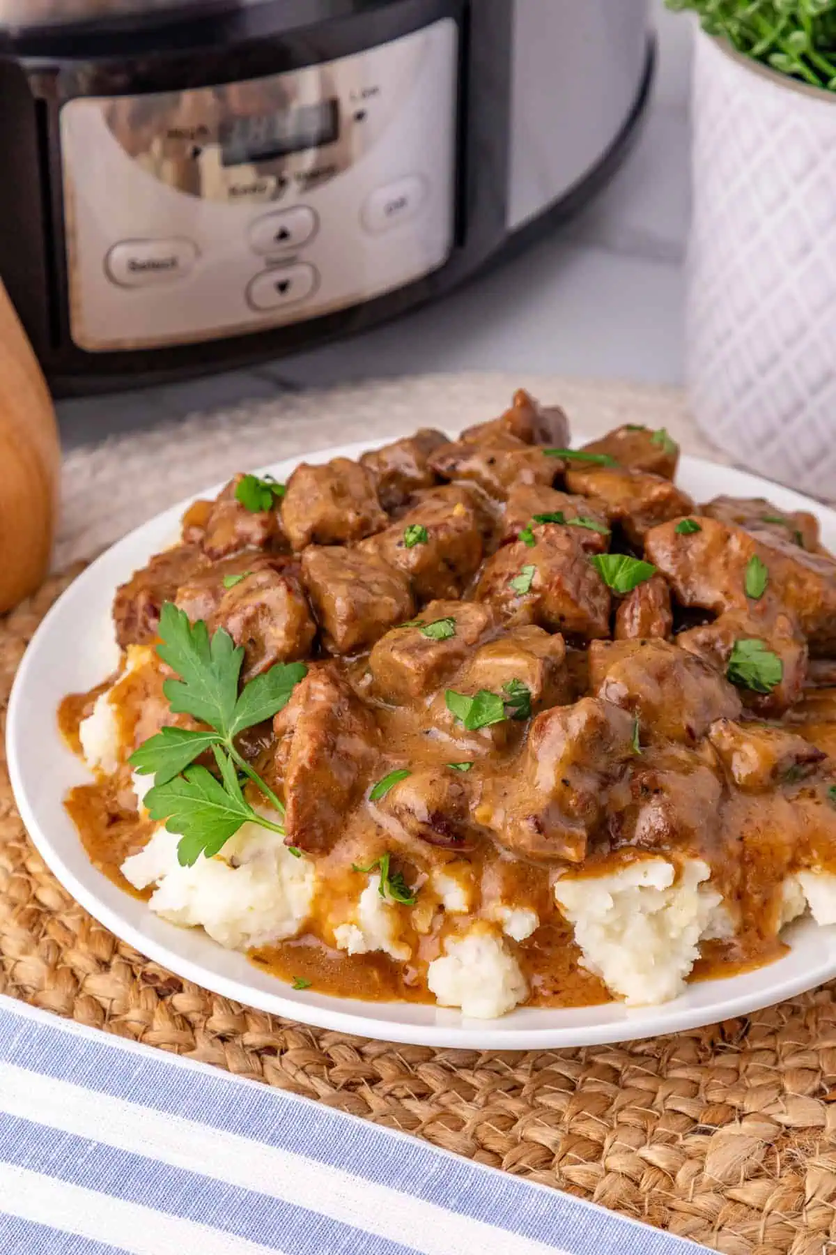 Crockpot beef tips and gravy spooned over creamy mashed potatoes with fresh parsley