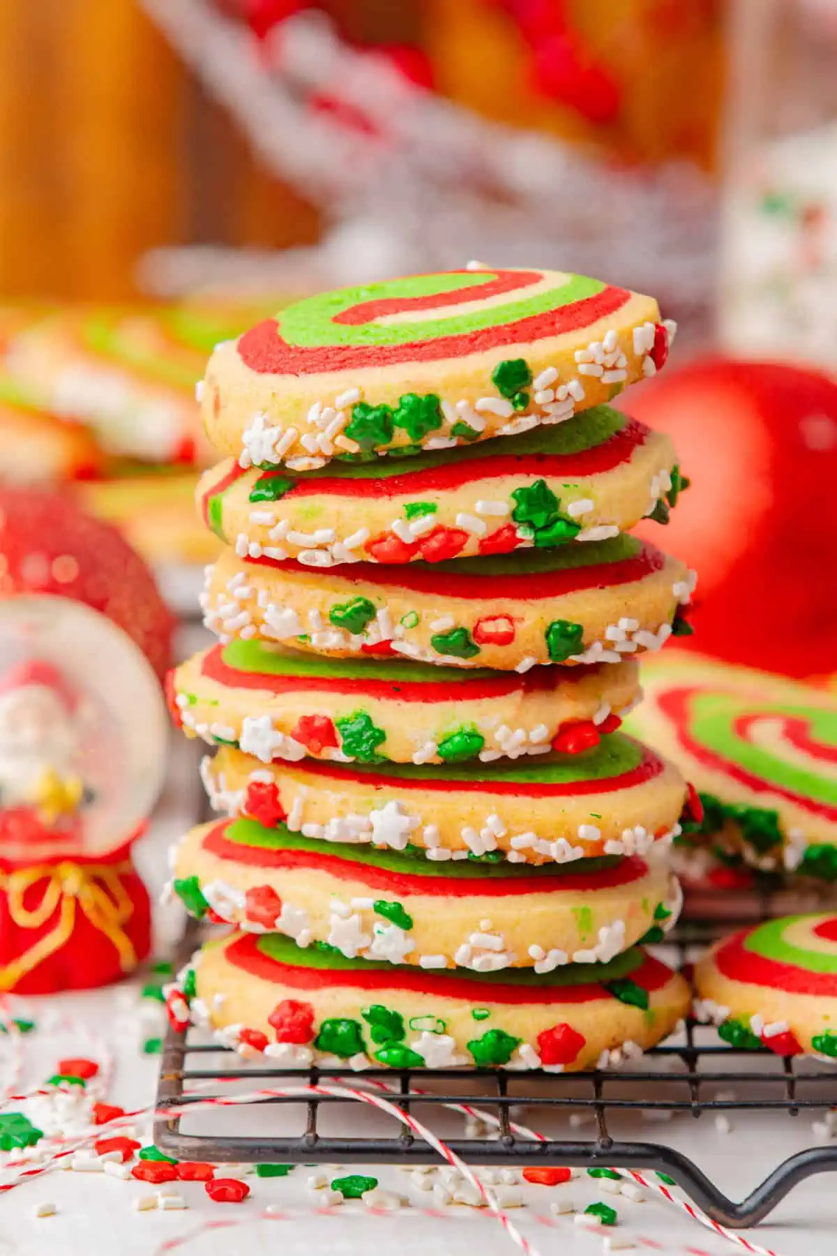 Red, white, and green pinwheel cookies stacked on a cookie rack