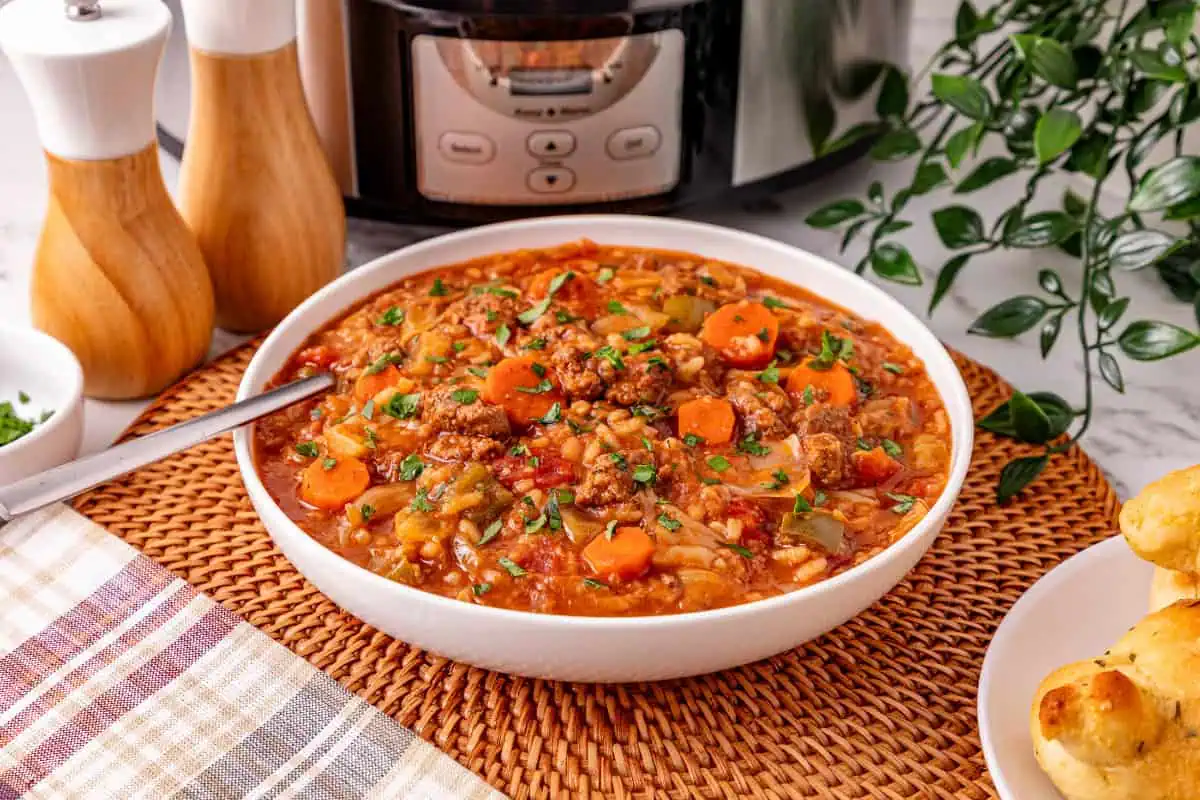 Bowl of crockpot cabbage roll soup with ground beef, cabbage, rice, and carrots in a tomato broth, topped with fresh parsley