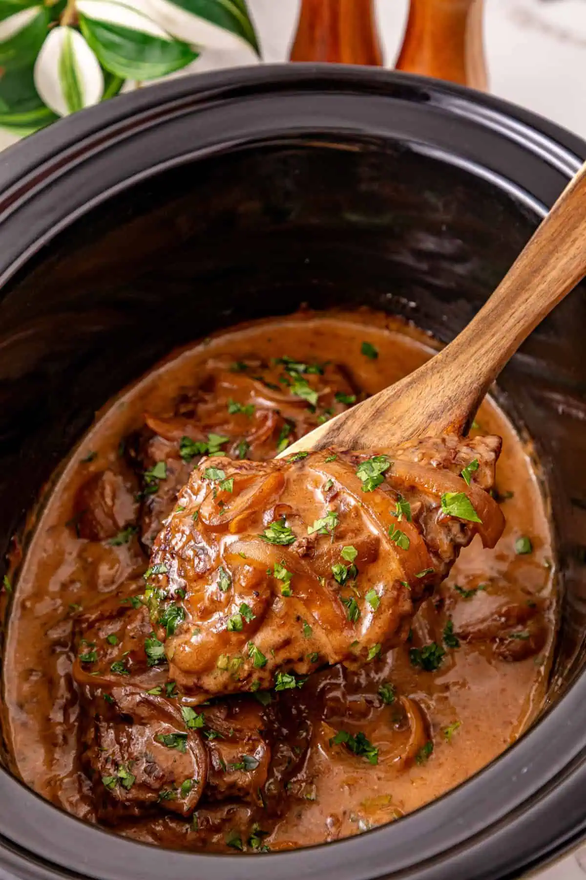 Fork-tender Crockpot cube steaks in onion gravy topped with chopped parsley.