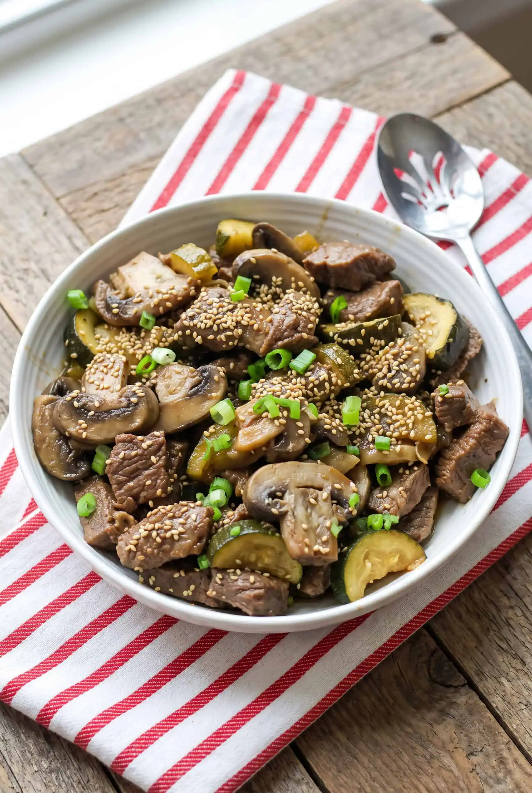 Instant Pot hibachi steak bites with mushrooms and zucchini in a white bowl, topped with sesame seeds.